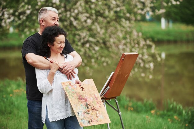 Dreamy look. Mature couple have leisure days and working on the paint together in the park