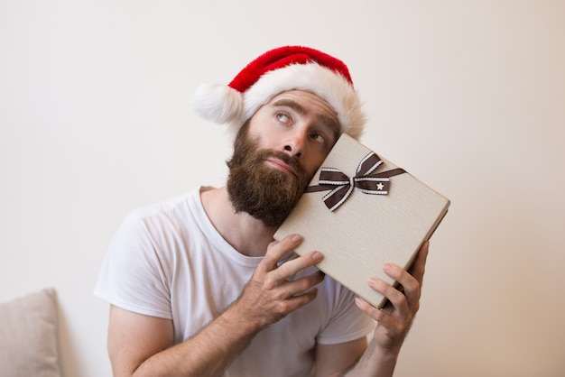 Мечтательный человек пытается угадать, что находится внутри рождественской подарочной коробке