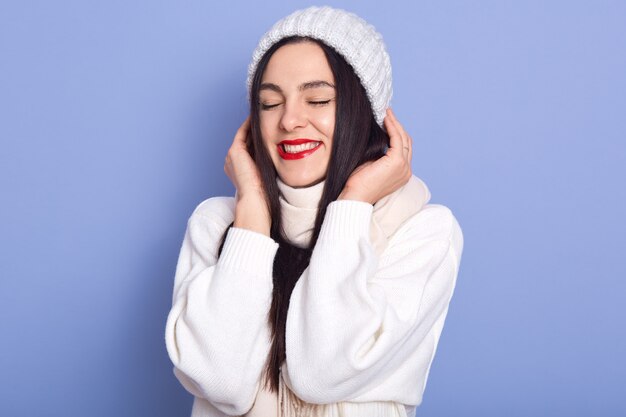 Dreamy pretty Caucasian brunette young female wearing white warm sweater