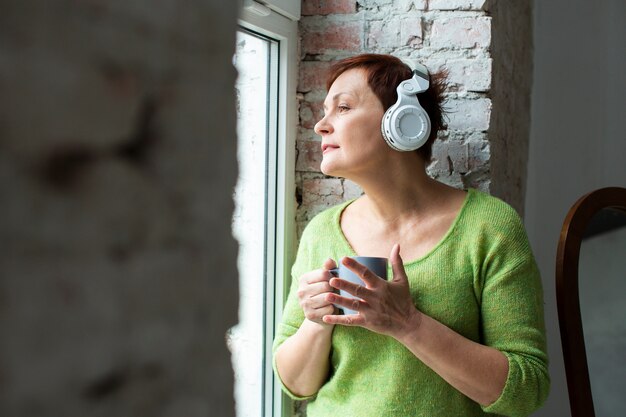 夢のような年配の女性が音楽を聴く