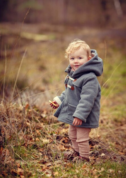 Dreamy shot of an adorable Caucasian toddler girl looking at the camera and standing in countryside