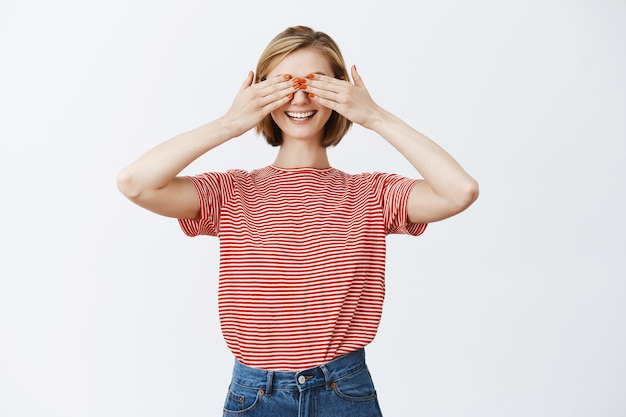 Dreamy smiling blond girl shut eyes and waiting for surprise