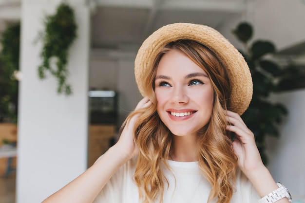 Dreamy smiling girl with pale skin looking up and touching fair curles