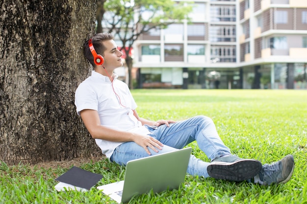 Dreamy teenage boy listening to music outdoors