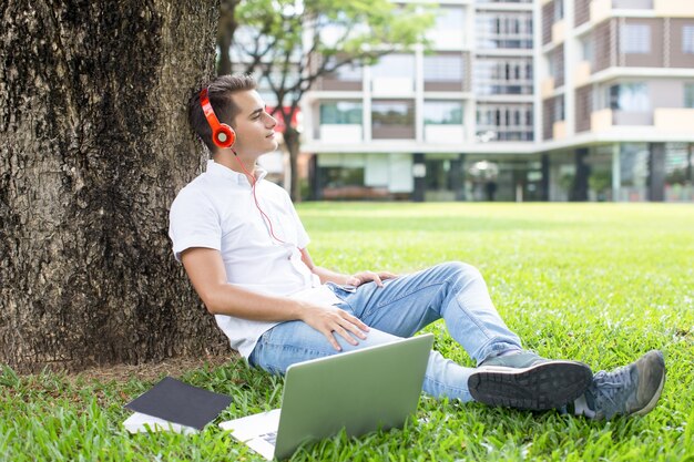 Dreamy teenage boy listening to music outdoors