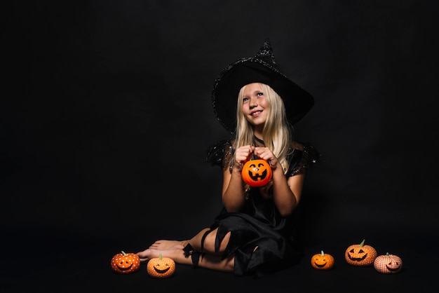 Free photo dreamy witch amidst jack-o-lanterns