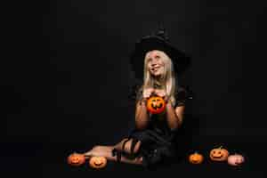 Free photo dreamy witch amidst jack-o-lanterns