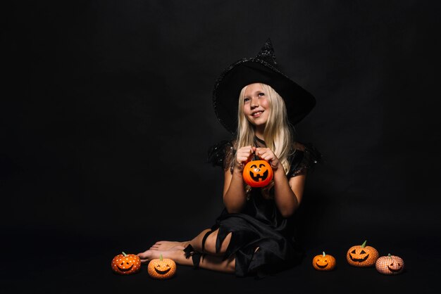 Dreamy witch amidst jack-o-lanterns