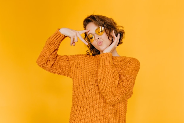 Dreamy woman in trendy sweater posing with kiss face expression and eyes closed