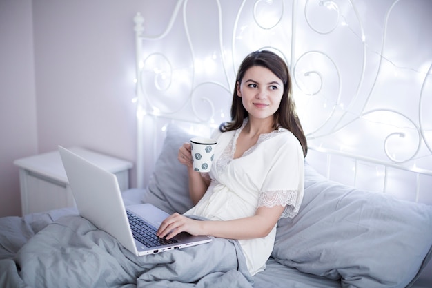 Dreamy woman with cup and laptop