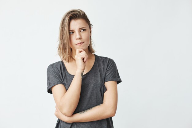 Dreamy young beautiful girl thinking with hand on chin looking in side .