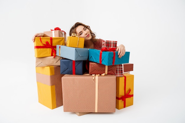 Бесплатное фото Мечтательная молодая кудрявая женщина среди подарочных коробок