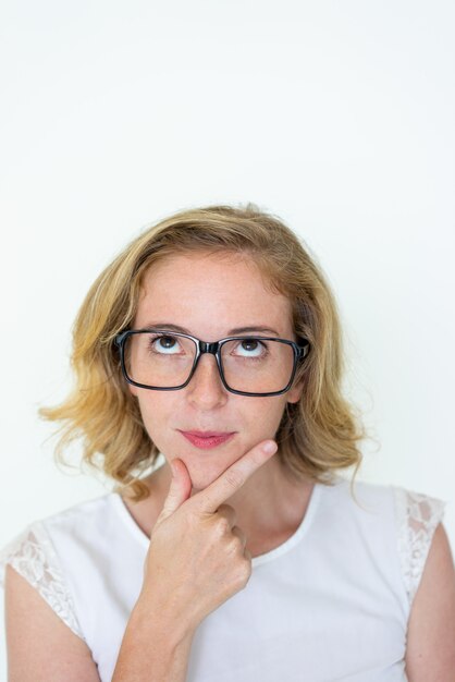 Dreamy young woman touching chin and looking upwards