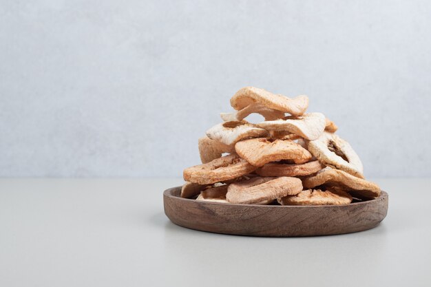 Dried apple chips on wooden plate
