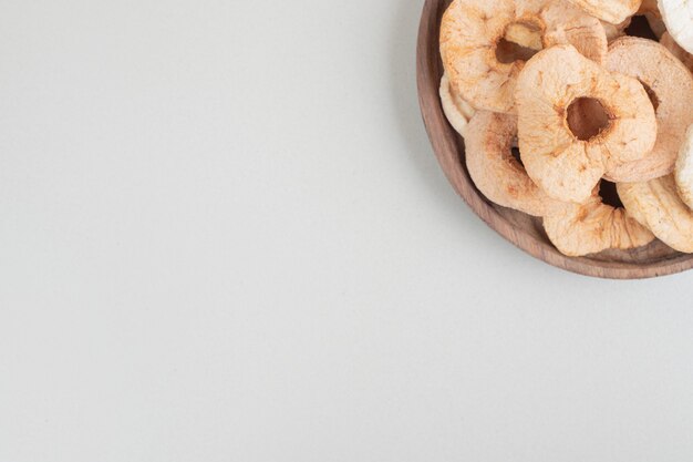 Dried apple chips on wooden plate