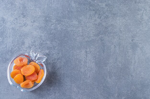 Dried apricot in a glass bowl , on the marble background.