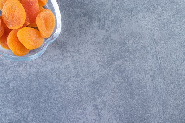 Dried apricot in a glass bowl , on the marble background.