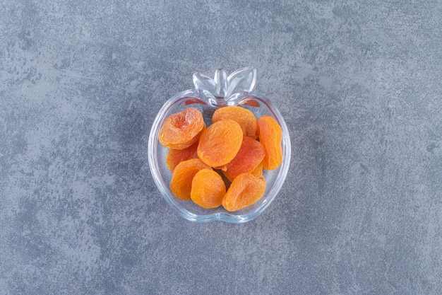 Free photo dried apricot in a glass bowl on the marble surface