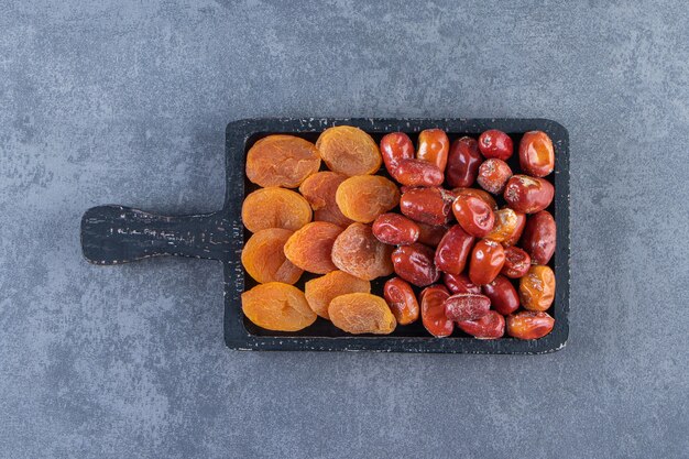 Dried apricot and oleaster on a board, on the marble background.