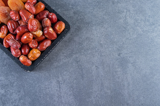 Free photo dried apricot and oleaster on a board, on the marble surface