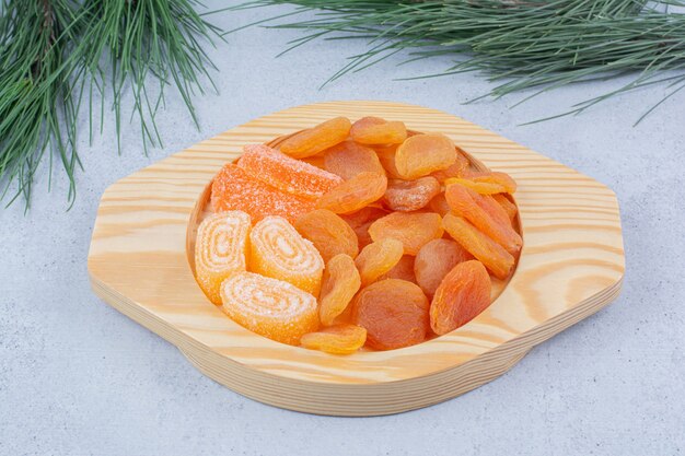 Dried apricots and marmalades on wooden plate. 