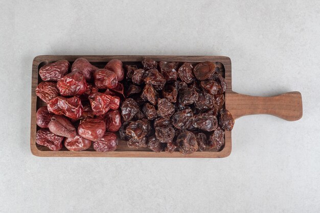 Dried black and brown plums on a wooden platter.