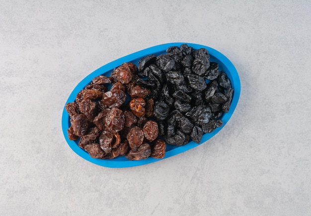 Dried black cherry and plums in a blue platter.