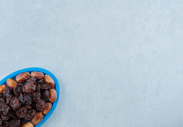 Free photo dried black plums with jujube berries in a blue platter. high quality photo