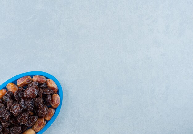 Dried black plums with jujube berries in a blue platter. High quality photo