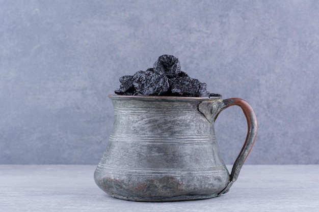 Dried black sultana in a bowl on concrete background. High quality photo