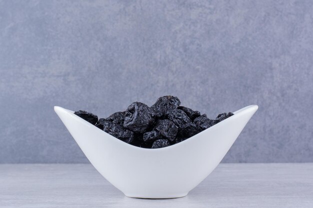 Dried black sultana in a bowl on concrete background. High quality photo