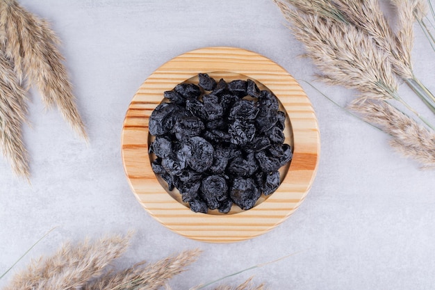 Free photo dried black sultanas in a plate on concrete background. high quality photo