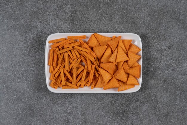 大理石の表面のプレートに乾燥パンチーズ風味のコーン型コーンチップス