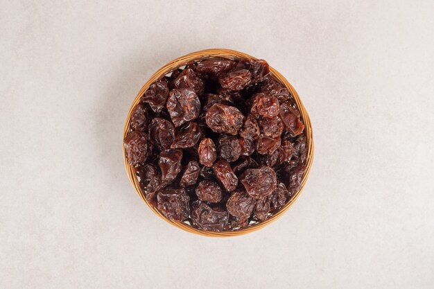 Dried brown plums in a ceramic cup or bowl.