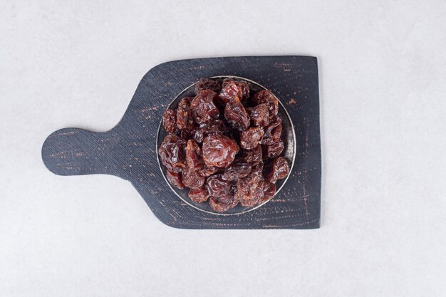 Dried brown plums on a wooden platter.