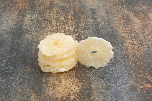 Anelli di ananas canditi secchi su fondo di marmo. foto di alta qualità