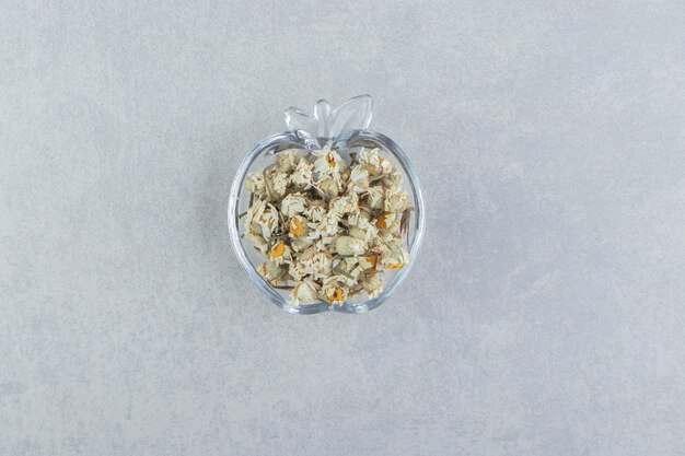 Dried chamomile flowers in glass bowl.  