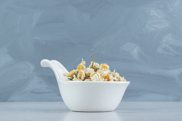 Dried chamomile flowers in white bowl