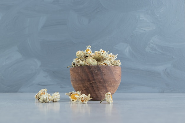 Dried chamomile flowers in wooden bowl.  