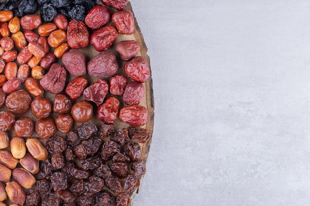 Сушеные вишни, ягоды и финики на деревянном блюде. Фото высокого качества