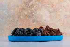 Free photo dried cherry and plums in a blue platter.