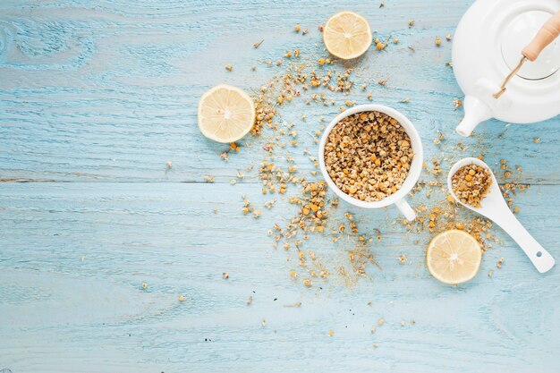 Dried chinese chrysanthemum flowers and slices of lemon with teapot on textured wooden table