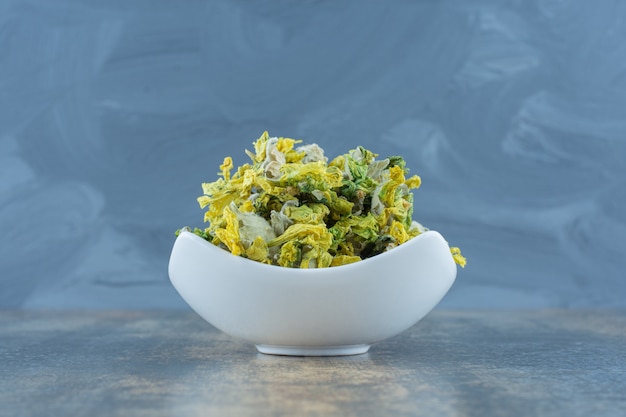 Dried chrysanthemum flower in white bowl.