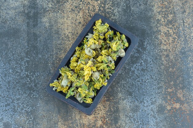 Dried chrysanthemum petals on black plate.