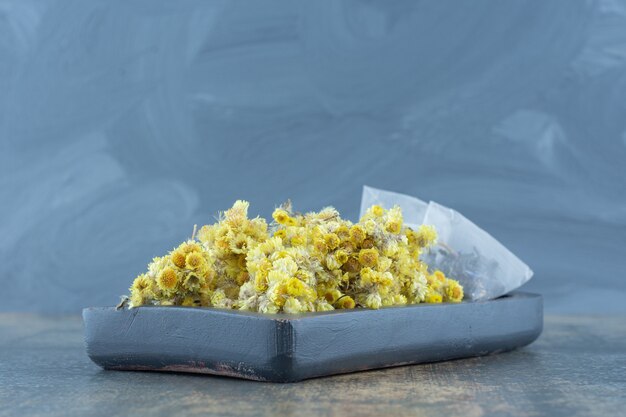 Free photo dried chrysanthemum and teabags on dark plate.