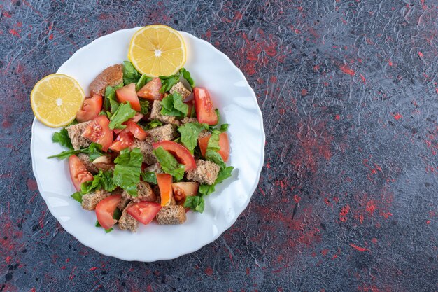 Сушеная корочка, смешанная с овощным салатом с лимонным гарниром на темном фоне. Фото высокого качества