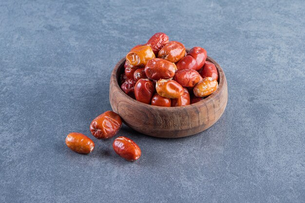 Dried elaeagnus in a wooden bowl, on the marble surface