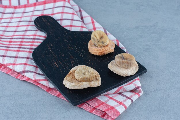 Dried figs on the cutting board, on the towel, on the tea towel, on the marble table. 