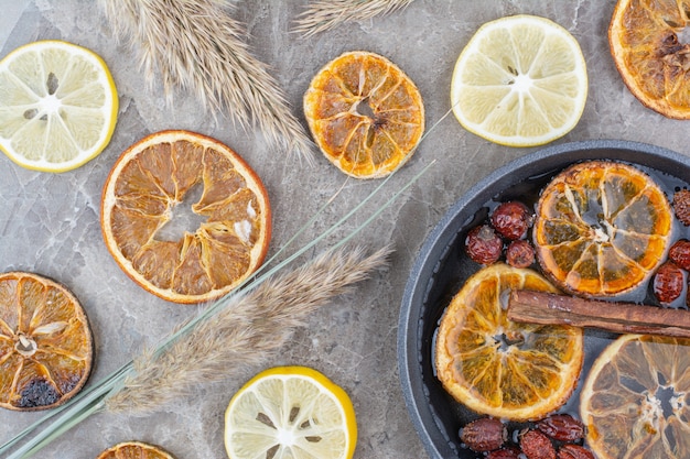 Free photo dried and fresh lemon slices with cinnamon on stone surface.