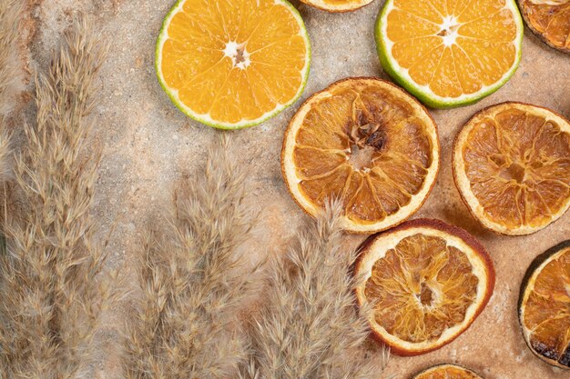 Сушеные и свежие дольки апельсина на мраморном фоне.